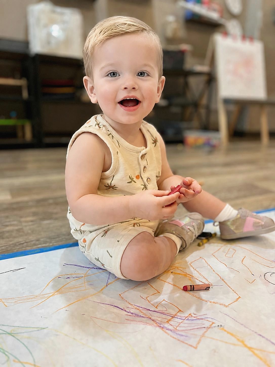 A smiling toddler drawing with a crayon at L&L Wicker Park.
